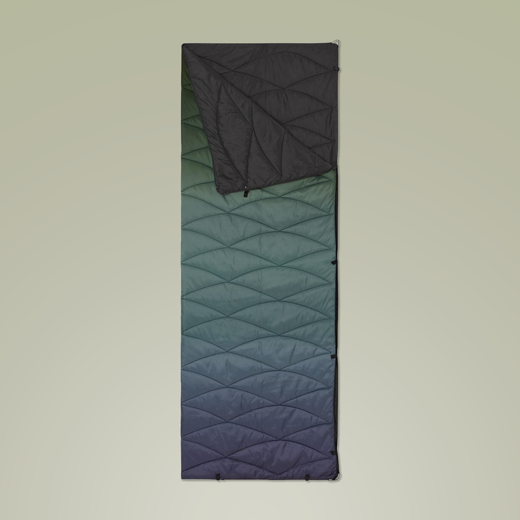 Quilted puffer blanket folded to show black and gradient sides