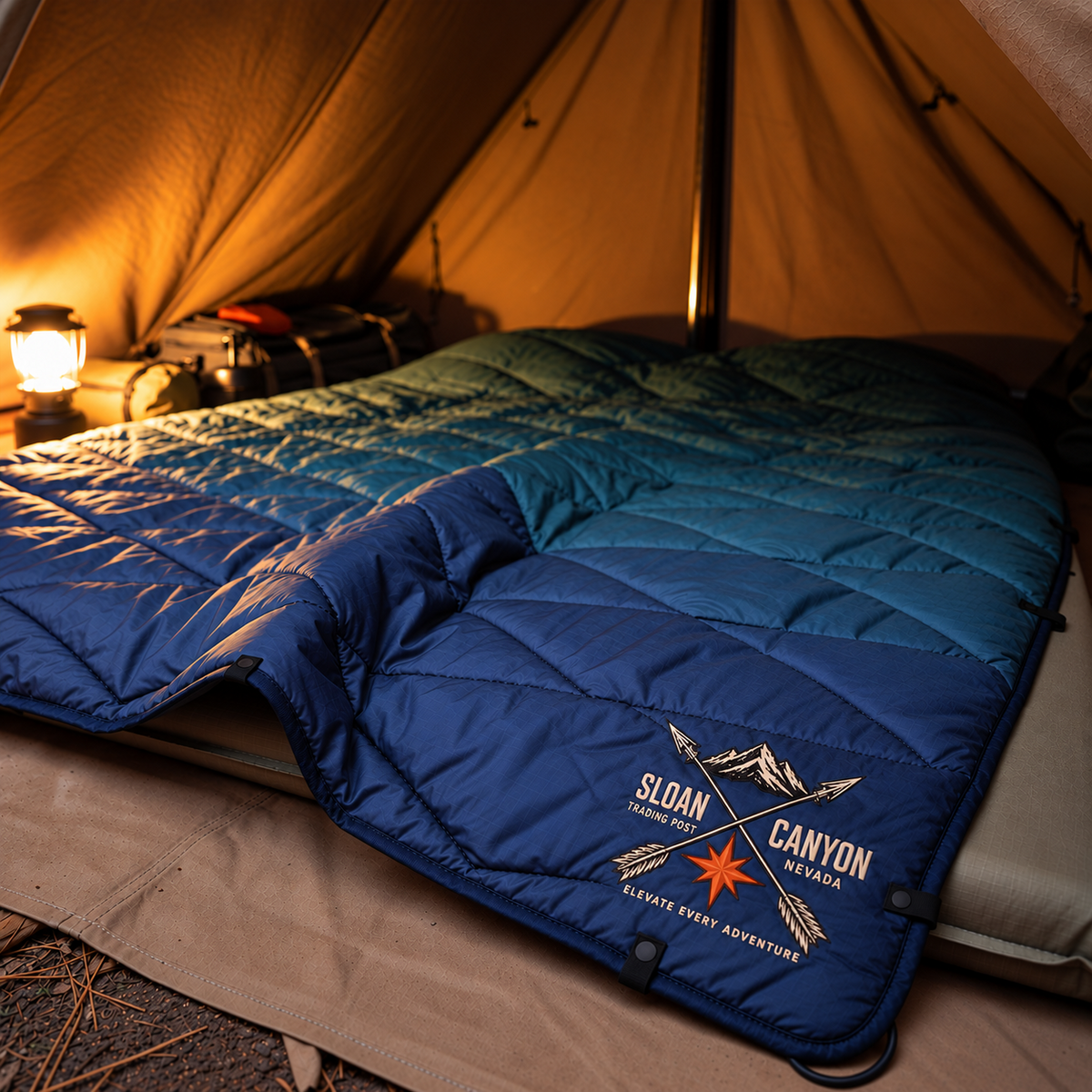 Sloan Canyon Trail Puffer Blanket by Nomadix inside a warmly lit tent
